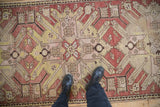 Abrashed terracotta ground with geometric starburst motifs on a distressed antique Kazak runner.