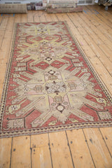 Angled view of an antique Kazak runner's large-scale starburst design and abrashed ground.