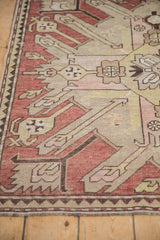 Close view of the worn, hand-knotted pile and geometric patterns on a distressed Kazak rug.