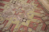 Large-scale starburst motif in dusty chestnut, terracotta, and lime green on an antique Kazak runner.