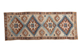 Distressed vintage Kars rug runner with large diamond medallions in dusty blue, copper, and sand tones.