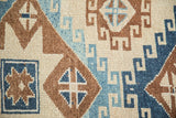 Textured close-up of a vintage Kars rug's geometric hook-and-latch pattern in blue and copper.