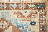 Hook-and-latch motifs and a narrow geometric border on a distressed hand-knotted Kars rug.