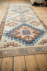 Perspective view down a vintage Kars rug runner highlighting its column of diamond medallions.