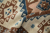 Close view of the hand-knotted pile on a distressed Kars rug in camel, blue, and copper tones.