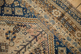 Evenly worn, hand-knotted pile on a vintage Qashqai carpet corner with navy, bronze, and dusty rose motifs.