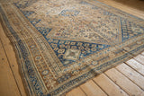 Side angle of a distressed Persian Qashqai carpet highlighting its bronze and blue motifs.
