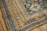 Low-pile texture of a distressed Qashqai rug corner with intricate bronze and blue geometric borders.