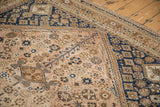 Geometric motifs in navy and bronze on the distressed corner of a vintage Qashqai rug.