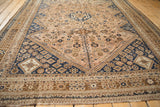 Angled view of a distressed Qashqai carpet's diamond medallion and geometric field.