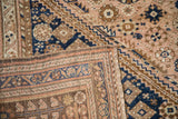 A vintage Qashqai rug's corner folded to show the hand-knotted back and worn pile.