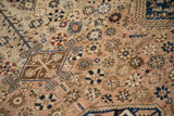 Geometric tendrils and floral blossoms on the low, worn pile of a vintage Persian carpet.