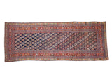Antique Malayer runner with colorful boteh motifs on a navy field, framed by elaborate brick red floral borders.