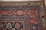 Corner detail of an antique Malayer rug with multi-tiered floral borders in brick red and navy blue.