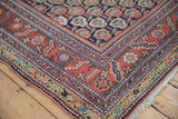 Detailed corner of an antique Malayer rug with multi-tiered floral borders and short ivory fringe.