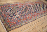 A long perspective on an antique Persian Malayer runner with a dense navy field of colorful botehs.