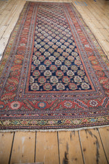 Angled view of an antique Malayer runner with its repeating boteh pattern and tiered floral borders.