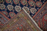 Corner view of an antique Malayer rug displaying the multi-tiered floral border and hand-knotted weave.