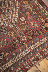 Angled detail of an antique Qashqai runner's field with scattered botehs and floral motifs.