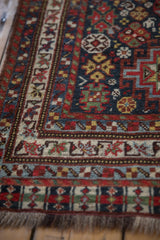 Corner of an antique Qashqai runner showing its even pile and geometric borders in sapphire blue and madder red.