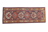 Antique Kazak rug runner with a column of octagonal medallions in brick red, navy blue, and dusty gold.