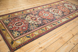 Antique Kazak runner from an angle, showcasing the bold column of geometric octagonal medallions.