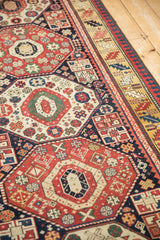 Detailed view of geometric medallions and the serrated leaf border of an antique Kazak rug.