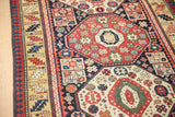 Angled detail of the antique Kazak's octagonal medallion and reciprocating pawn design border.