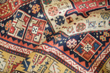 A close view of the low hand-knotted pile and octagonal motifs of an antique Kazak rug runner.