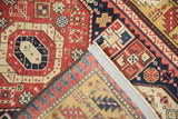 Folded corner detail of an antique Kazak rug, revealing the weave's back and reinforced side cord.