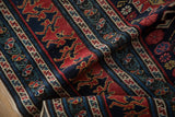 Reciprocating dragon motifs in brick red on the multi-tiered navy blue border of an antique Shirvan rug.