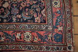 Expressively drawn floral border in dusty blush on a hand-knotted navy blue vintage Bijar rug.
