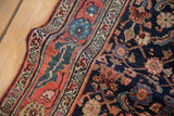 Angled view of the hand-knotted Bijar rug's expressive floral border and navy Herati field.