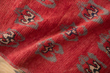 Textural close-up of vintage Oushak rug, showing red, gray, navy, and rose floral motifs.
