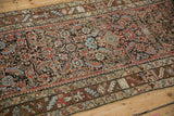 Close-up of the antique Persian runner's border showing the date cartouche and low pile.