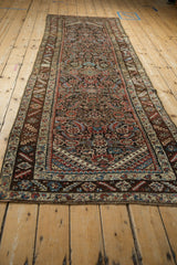 Low angle perspective of an antique Persian runner, showing its full length and intricate Herati pattern.