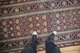 Looking down at the intricate geometric guls and floral borders of a Persian Malayer runner.