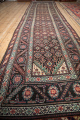 Angled view down the length of an antique Malayer runner, revealing its natural hand-knotted shape.