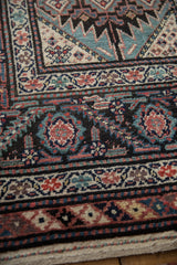 Angled detail of the antique Malayer rug's intricate geometric and floral borders and low pile.