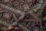 A folded antique Malayer runner shows the short pile and detailed geometric motifs and serrated leaf borders.