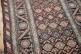 Close view of geometric guls and the serrated leaf and floral main border on an antique rug.