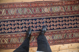 A downward view of an antique Malayer runner's navy boteh motifs and intricate floral borders.