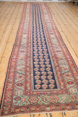 Angled view of an antique Malayer runner, showing the full length, boteh pattern, and gentle contour.