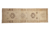 Distressed vintage Oushak runner with geometric medallions and even wear in tones of sand and pale brown.