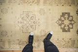 Evenly worn, low-pile texture of a vintage Oushak runner with geometric medallions in cream and sand.