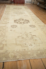 Angled view down the length of a distressed Oushak runner showing its repeating medallions.
