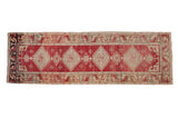 Distressed Oushak runner with ivory diamond medallions, an abrashed cherry red field, and geometric borders.