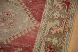 Intricate serrated leaf border and distressed cherry red field of a vintage Oushak rug runner.