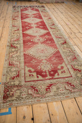 Angled view down the length of a distressed Oushak runner, showing its repeating diamond medallions.