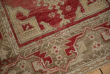 The distressed, hand-knotted texture of an Oushak runner in cherry red and pale bronze tones.